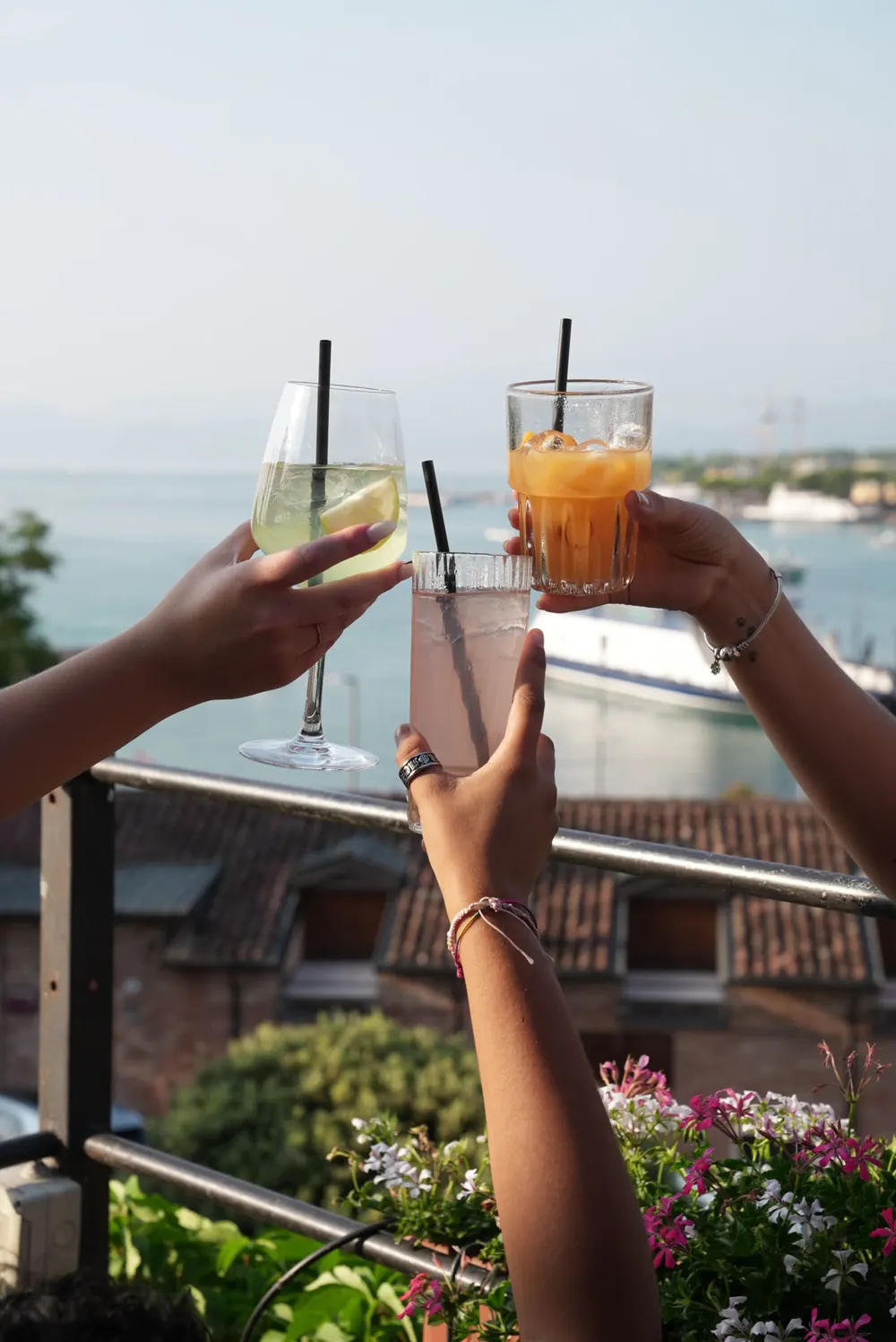 Brindisi con tre drink sulla terrazza del Kiosko, con il Lago di Garda sullo sfondo